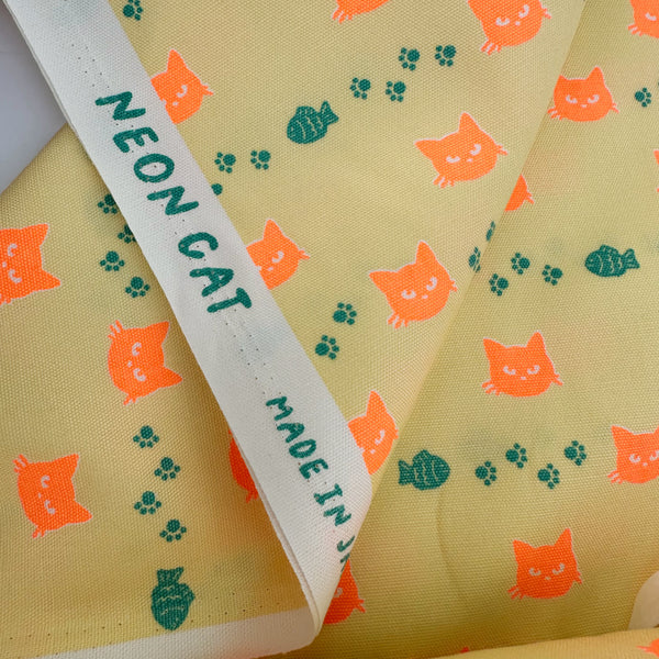 Selvage of Neon Cat Cotton Oxford Fabric in Yellow featuring a playful print of fish, paws, and neon cat faces, imported from Japan.