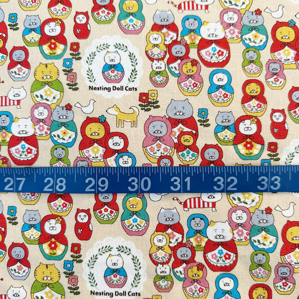 Scale of Nesting Dolls Cats Cotton Canvas Fabric by Cotton Kobayashi, style KTS-7177A, featuring cat nesting doll illustrations, in beige, imported from Japan