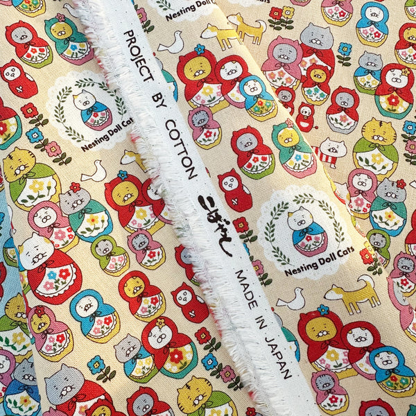 Selvage of Nesting Dolls Cats Cotton Canvas Fabric by Cotton Kobayashi, style KTS-7177A, featuring cat nesting doll illustrations, in beige, imported from Japan