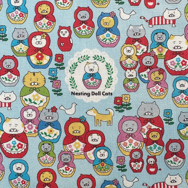 Close up of Nesting Dolls Cats Cotton Canvas Fabric by Cotton Kobayashi, style KTS-7177C, featuring cat nesting doll illustrations, in blue, imported from Japan