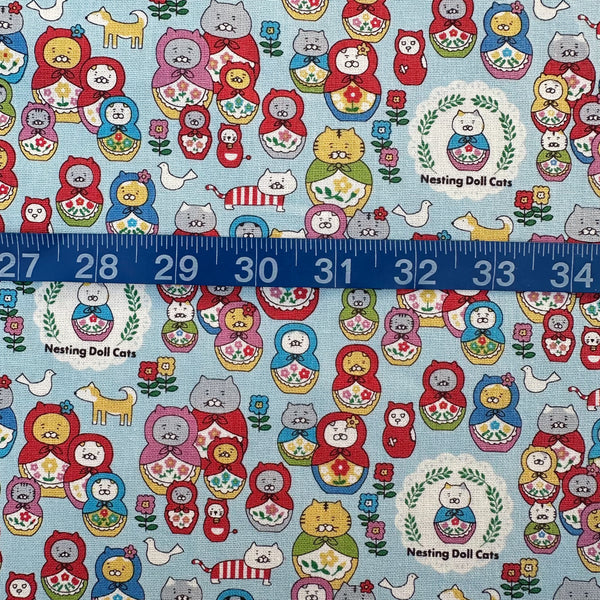 Scale of Nesting Dolls Cats Cotton Canvas Fabric by Cotton Kobayashi, style KTS-7177C, featuring cat nesting doll illustrations, in blue, imported from Japan