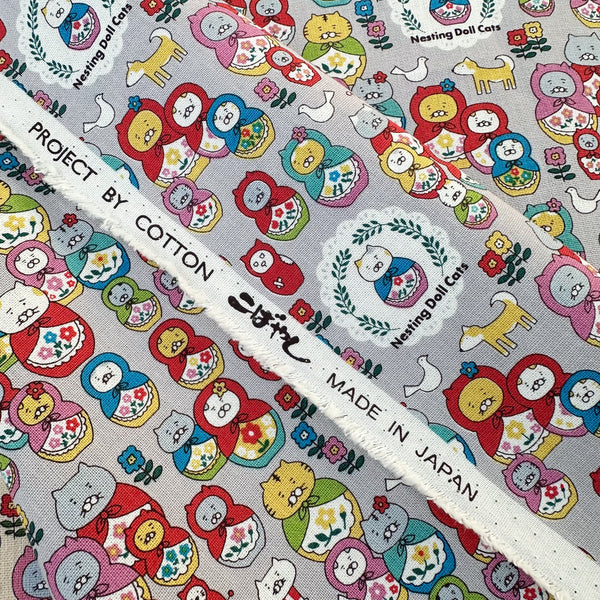 Selvage of Nesting Dolls Cats Cotton Canvas Fabric by Cotton Kobayashi, style KTS-7177D, featuring cat nesting doll illustrations, in gray, imported from Japan