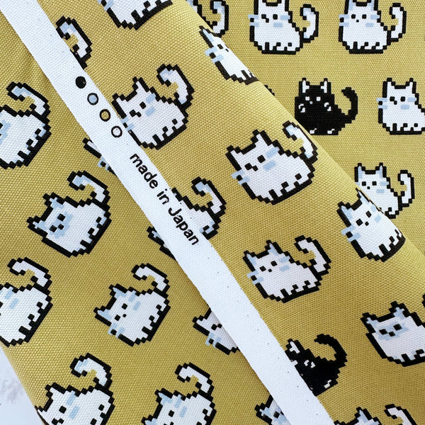 Selvage of Pixel Cats cotton oxford fabric in golden mustard with playful pixel-style cat print, imported from Japan