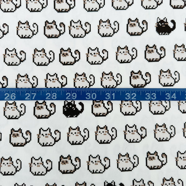 Scale of Pixel Cats white cotton oxford fabric featuring a repeating pattern of pixel-style cat motifs arranged in rows.