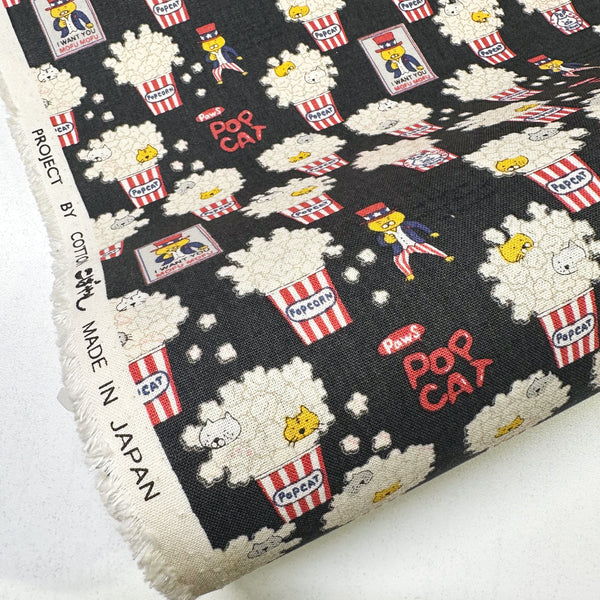 Bolt of Pop Cat canvas fabric in black cotton linen blend by Cotton Kobayashi featuring cats hiding in popcorn
