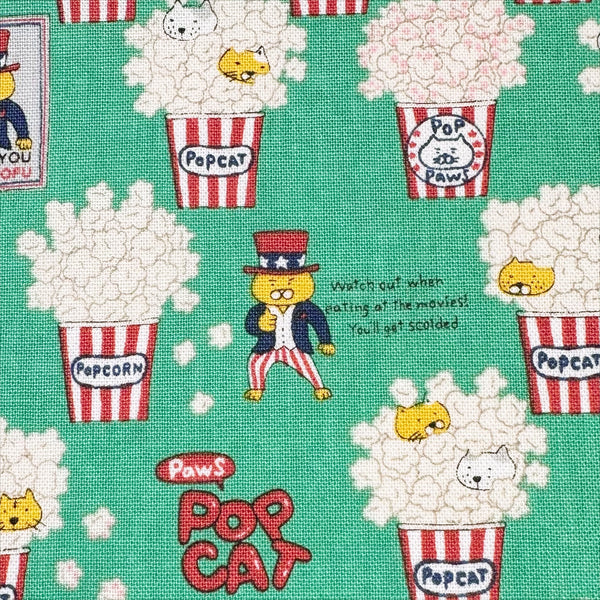 Close up of Pop Cat canvas fabric in green cotton linen blend by Cotton Kobayashi featuring cats hiding in popcorn