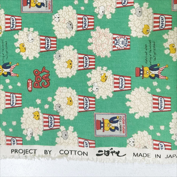 Selvage of Pop Cat canvas fabric in green cotton linen blend by Cotton Kobayashi featuring cats hiding in popcorn