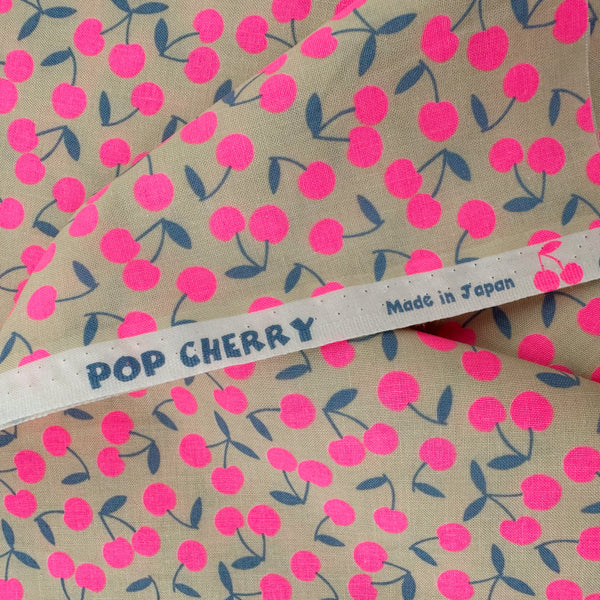 Selvage of Pop Cherry Cotton Fabric in Cream and Neon Pink featuring a bold cherry print, imported from Japan.