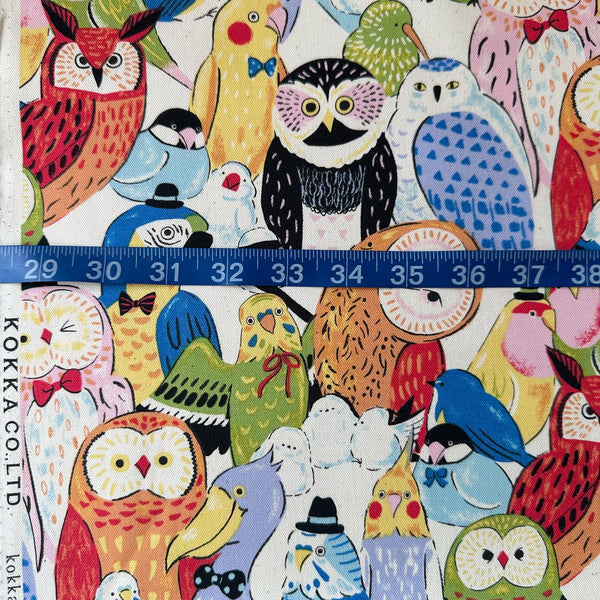 Powerful Animal Birds cotton oxford fabric by Kokka in natural, style YGA-81050-2A, shown with a tape measure for scale