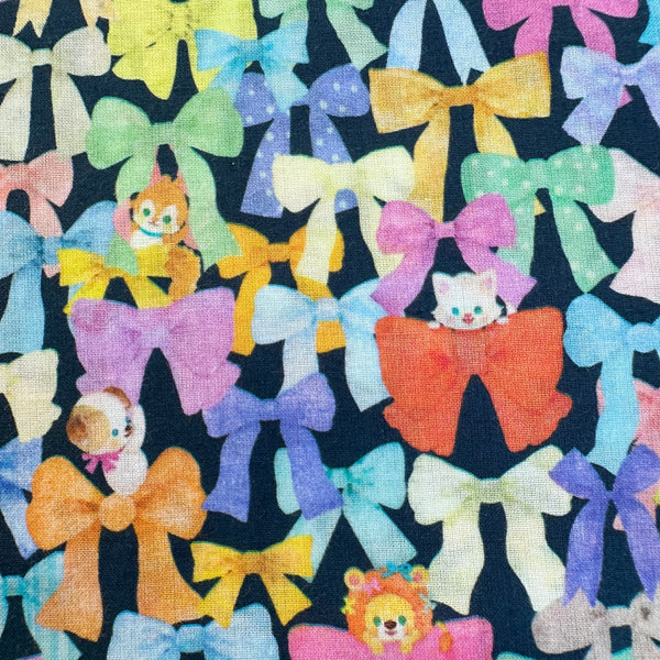 Close up of Ribbon Collector Cotton Lawn Fabric in Navy by Yukiemon for Hokkoh featuring whimsical ribbons and charming illustrated motifs on soft Japanese cotton lawn.