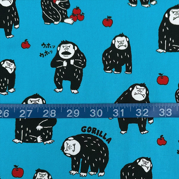 Scale of Silly Gorilla Cotton Oxford Fabric in Blue by Cosmo Textiles featuring animated gorillas and apples on a blue background.