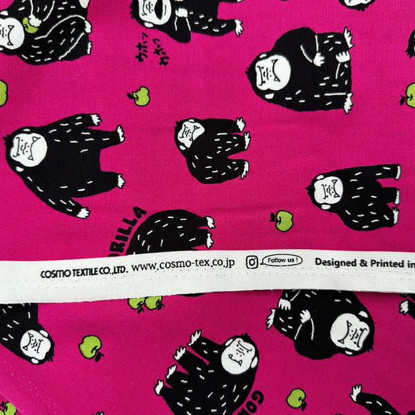 Selvage of Silly Gorilla Cotton Oxford Fabric in Pink by Cosmo Textiles featuring animated gorillas and apples on a pink background.