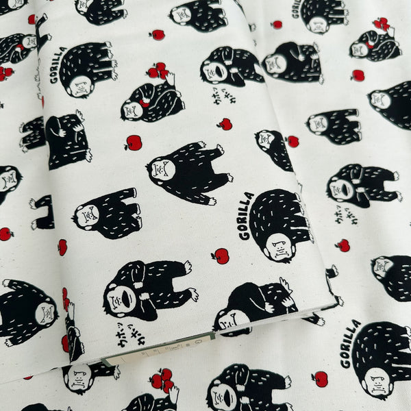 Bolt of Silly Gorilla Cotton Oxford Fabric in White by Cosmo Textiles featuring animated gorillas and apples on a white background.