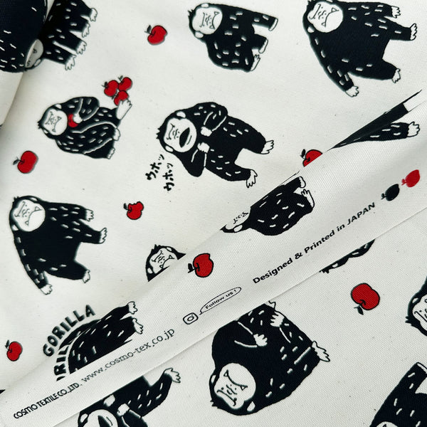 Selvage of Silly Gorilla Cotton Oxford Fabric in White by Cosmo Textiles featuring animated gorillas and apples on a white background.