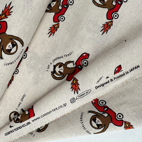 Selvage of Speedy Sloth Cotton Linen Blend Fabric by Cosmo Textiles, style AP65204 2A, featuring sloths in red racing cars, in natural
