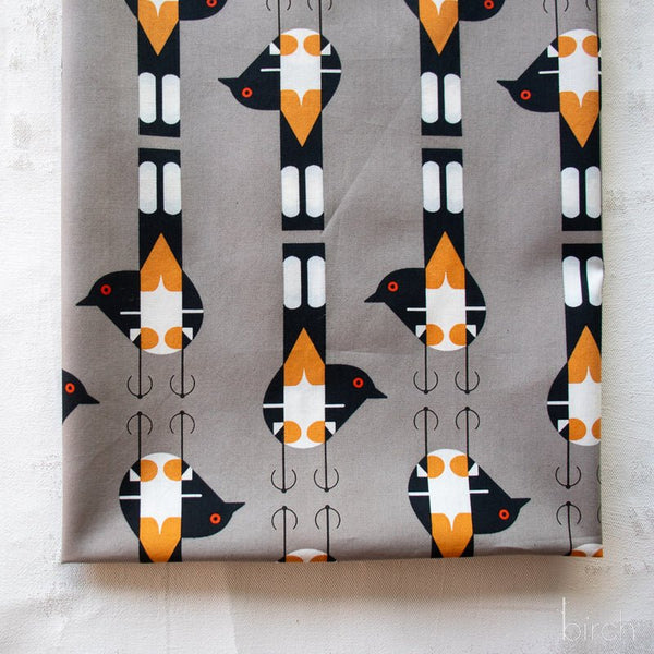 Stock photo of Spotted Tail Blackbird Shroom Poplin Fabric by Charley Harper for Birch Fabrics, featuring blackbirds in repeating pattern, on gray background