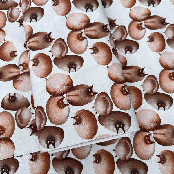 Bolt of Stone Cats cotton fabric in Brown by Nora featuring round stone cats with a quirky, surreal charm and slightly eerie appeal