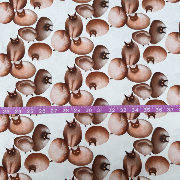 Scale of Stone Cats cotton fabric in Brown by Nora featuring round stone cats with a quirky, surreal charm and slightly eerie appeal
