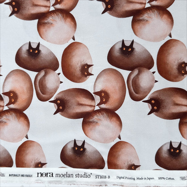 Selvage of Stone Cats cotton fabric in Brown by Nora featuring round stone cats with a quirky, surreal charm and slightly eerie appeal