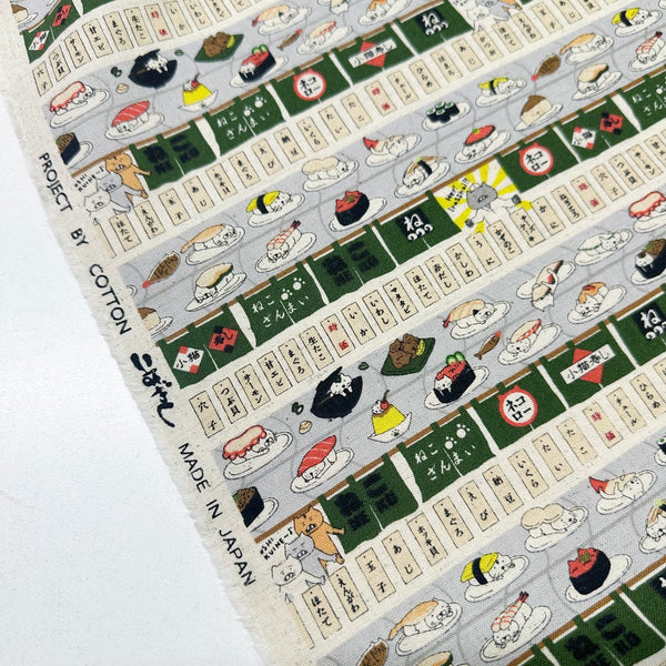 Selvage of Sushi Cats canvas fabric in green cotton linen blend by Cotton Kobayashi featuring playful cats and sushi illustrations