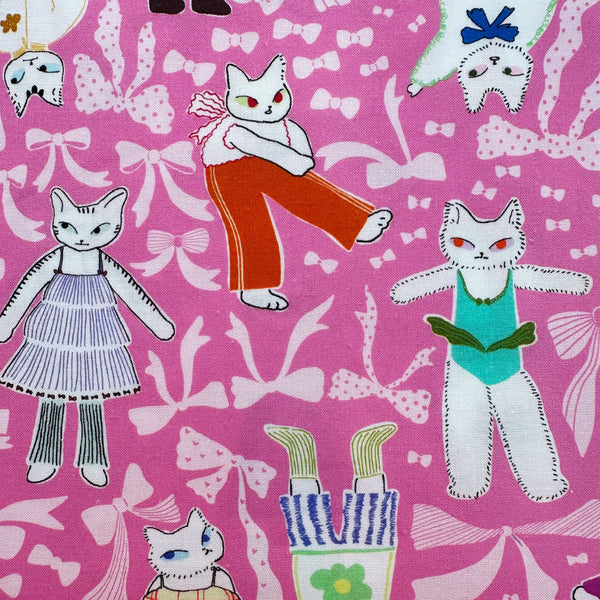 Close up of The Open Closet cotton fabric in pink by Nora featuring cats getting dressed in cute outfits with bows imported from Japan