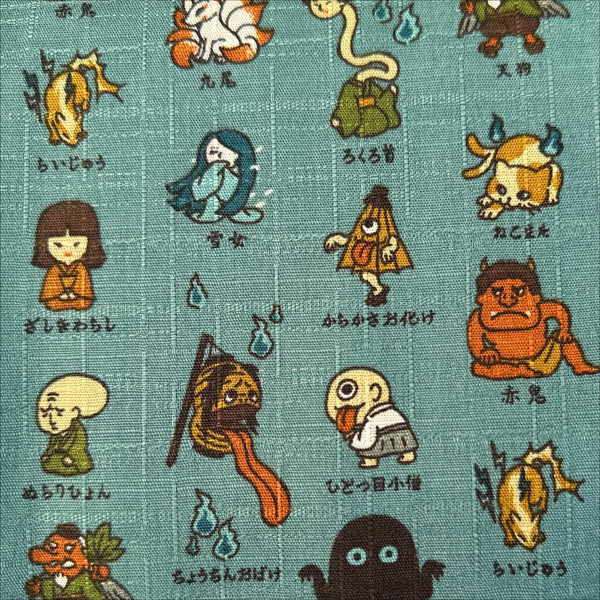 Close up of Yokai Guide Cotton Dobby Fabric by Cosmo Textiles, style AP62206 2B, featuring Japanese folklore spirits and monsters, in dusty jade, imported from Japan