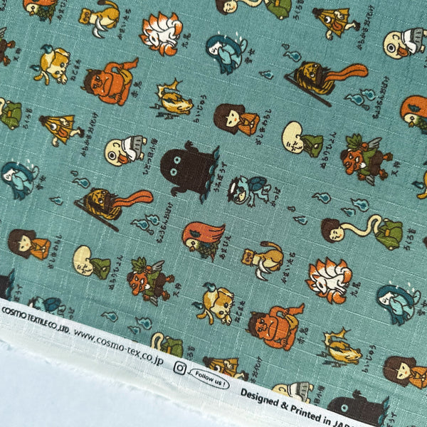 Selvage of Yokai Guide Cotton Dobby Fabric by Cosmo Textiles, style AP62206 2B, featuring Japanese folklore spirits and monsters, in dusty jade, imported from Japan